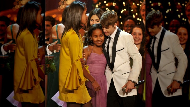 Justin Bieber hugging Sasha Obama as Malia Obama looks on
