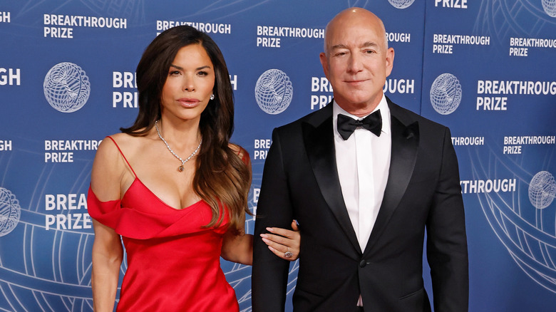 Lauren Sánchez wearing a red gown, alongside Jeff Bezos in a black tuxedo