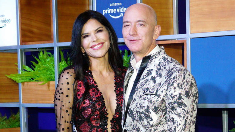 Lauren Sanchez posing with Jeff Bezos in front of an Amazon Prime video background
