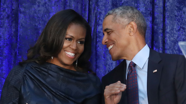 Michelle and Barack Obama smile at each other in 2018