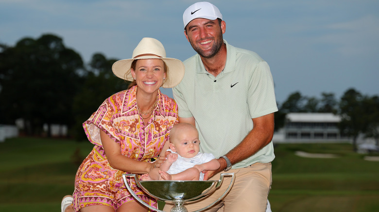 Meredith and Scottie Scheffler pose with their son in his FedEx trophy.