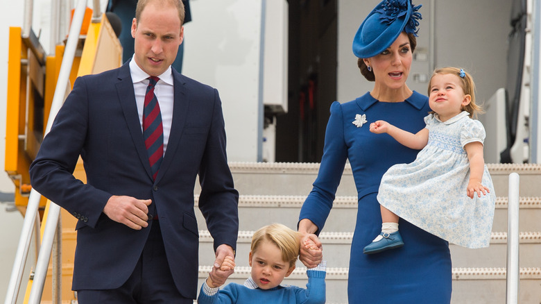 Prince William and Kate Middleton walking down the stairs of a plane with their kids