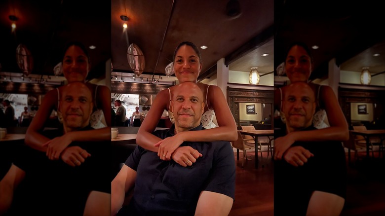 Alexis Lewis standing behind a seated Cory Booker with her arms around him
