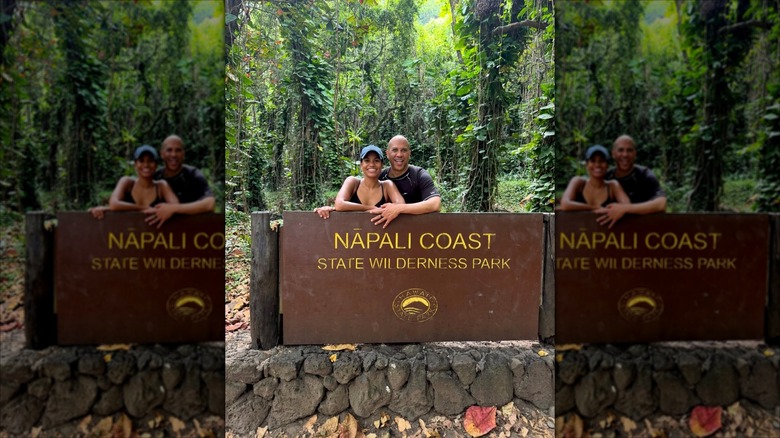 Alexis Lewis and Cory Booker posing behind a Nā Pali Coast State Wilderness Park sign.