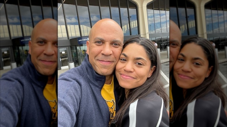 Alexis Lewis and Cory Booker pressing their cheeks together and taking a selfie outside Newark Liberty International Airport
