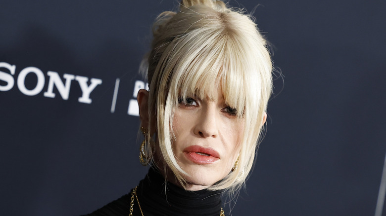 Kelly Osbourne wearing a black turtleneck with platinum blonde curtain banks hanging in her face