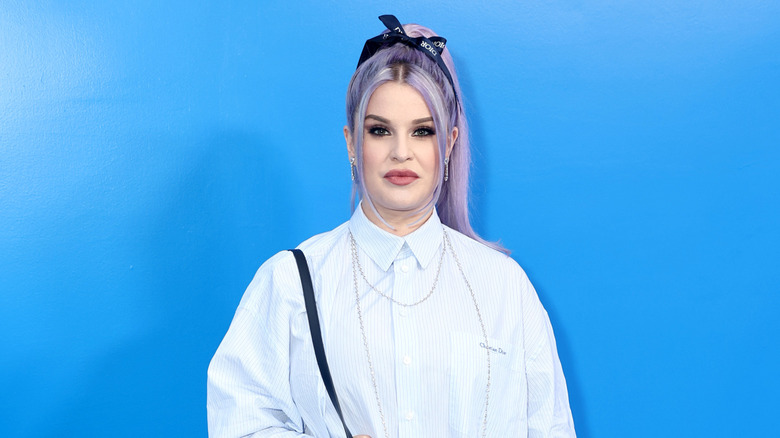 Kelly Osbourne wearing a striped collared shirt and a black bow headband