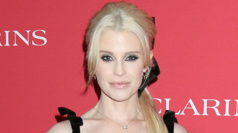 Kelly Osbourne wearing a black dress with bows on the straps and in her platinum blonde hair