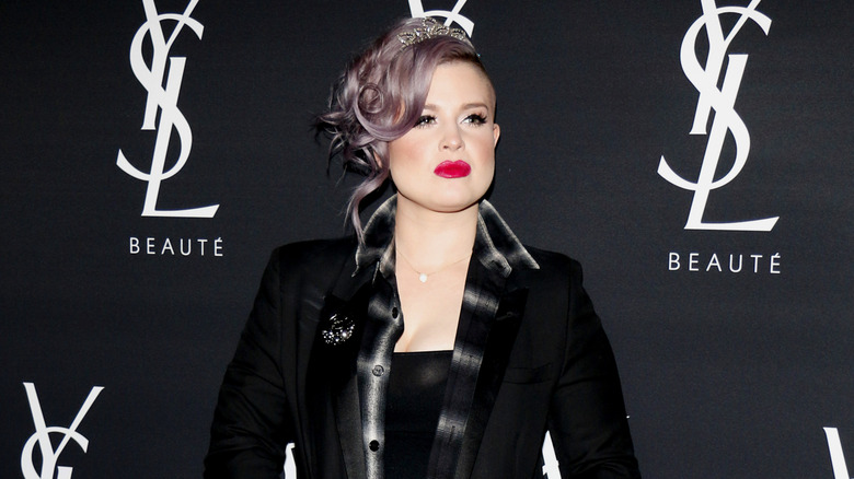 Kelly Osbourne wearing a black blazer and diamond tiara on the red carpet