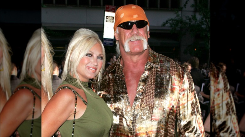 Dressed in a shimmery outfit, Hulk Hogan holds Linda Hogan's waist.