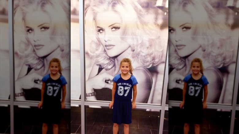 Young Dannielynn Birkhead poses in front of an Anna Nicole Smith photo.