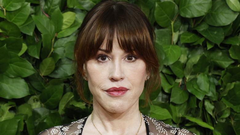 Molly Ringwald standing in front of a bunch of leaves