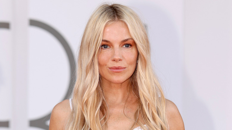 Actress Sienna Miller posing at an event with her hair down in soft waves