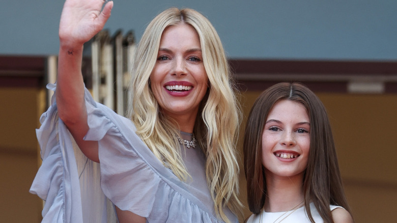 Sienna Miller waves and smiles beside her smiling daughter Marlowe Sturridge
