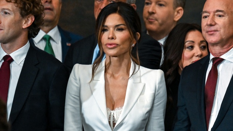 Wearing a lacy bra and a white suit, Lauren Sánchez sits between Jeff Bezos and Mark Zuckerberg.