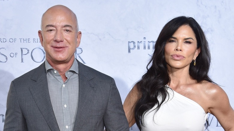 Jeff Bezos holds the arm of Lauren Sánchez, who is making a pout on the red carpet.