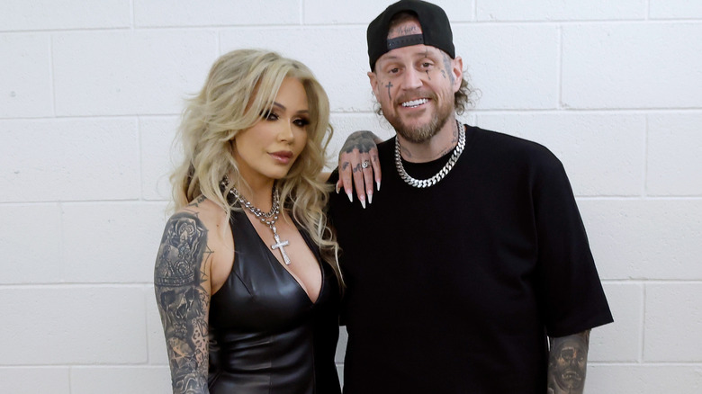 Bunnie Xo and Jelly Roll posing in front of a wall in all-black outfits