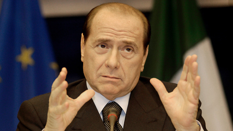 Silvio Berlusconi with his hands raised