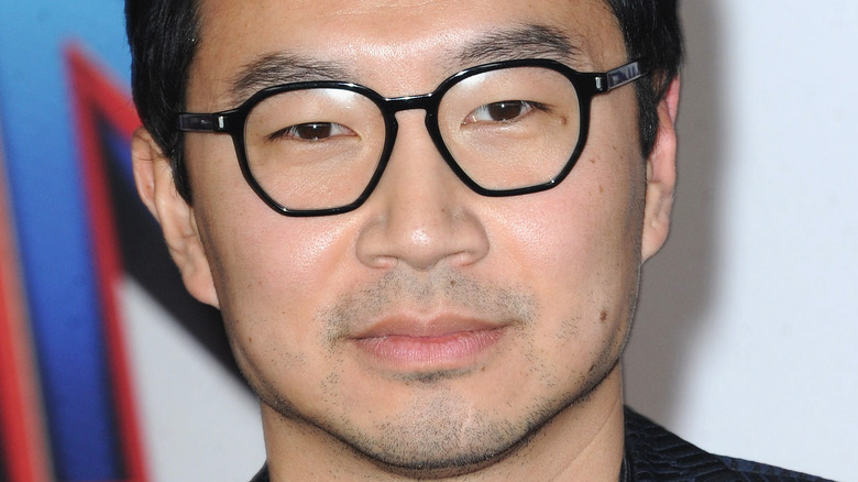 Simu Liu wears black glasses and a suit