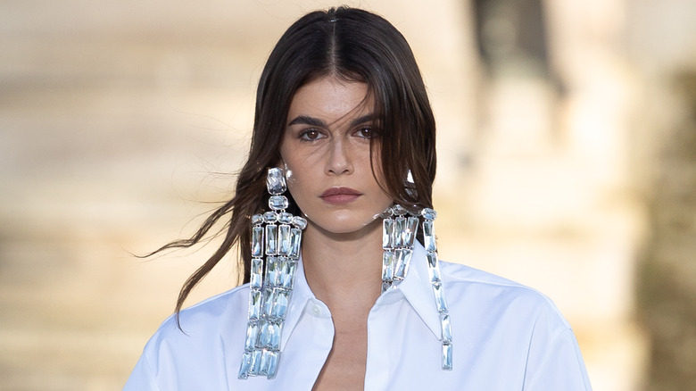 Kaia Gerber strutting on the runway in oversized earrings