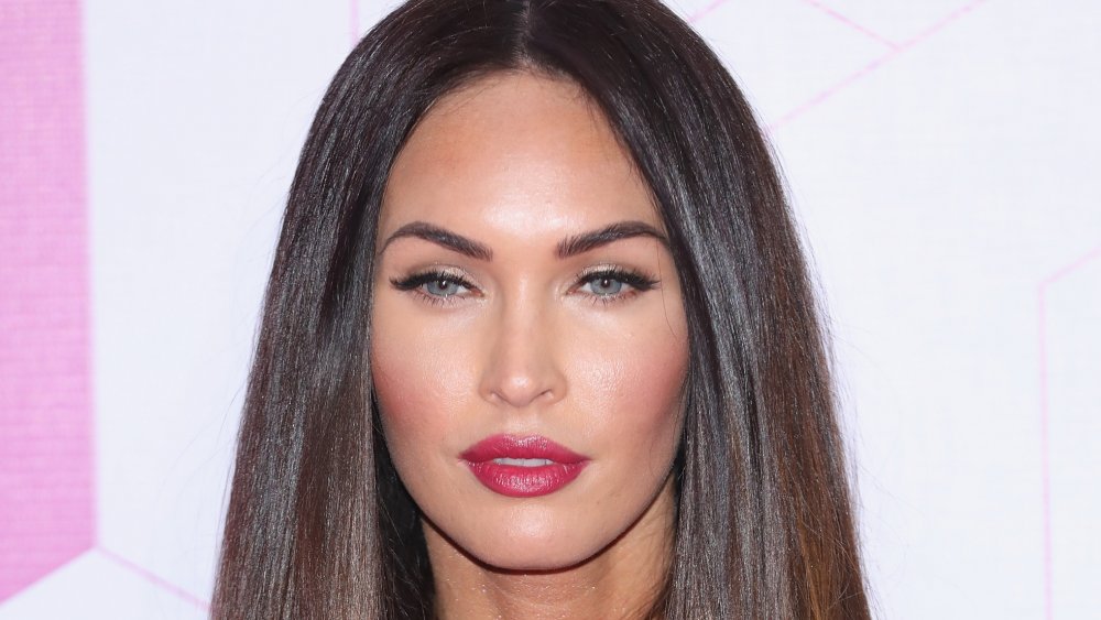 Megan Fox in a black floral-printed dress, posing with a serious expression
