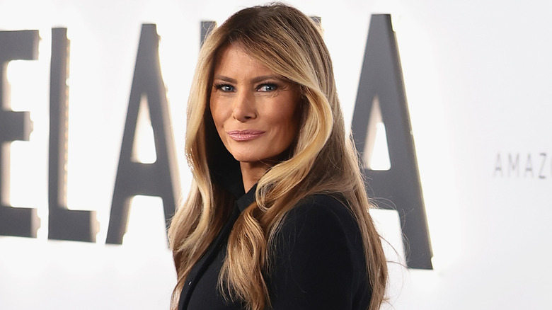 Melania Trump turning and smiling on the red carpet of her documentary premiere.