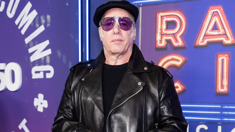 Andrew Dice Clay wearing a black leather jacket and black beret with colored sunglasses