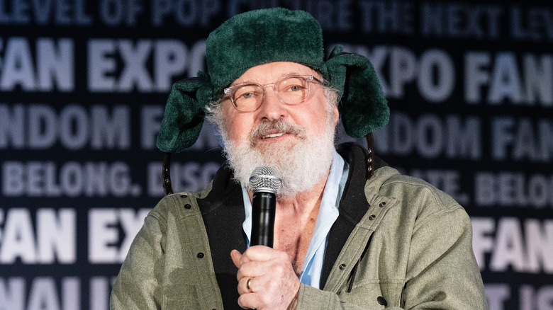Randy Quaid wearing a green hat while speaking at a fan convention