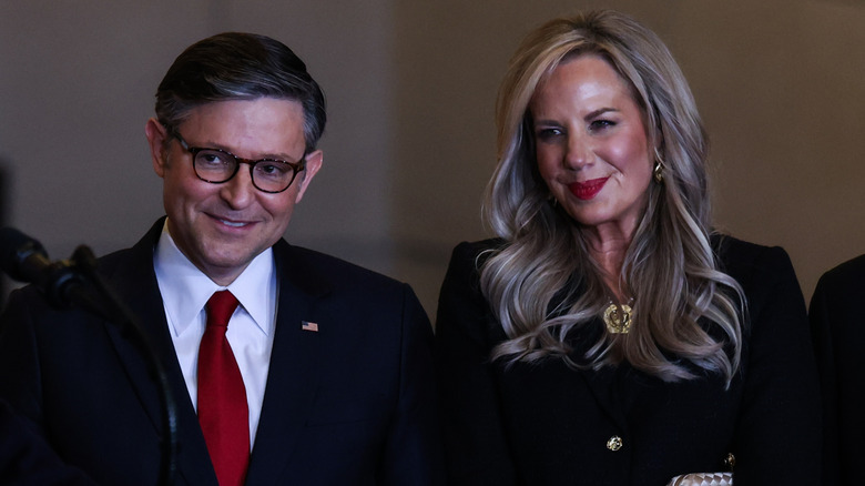 Mike Johnson and Kelly Lary smiling at Donald Trump.