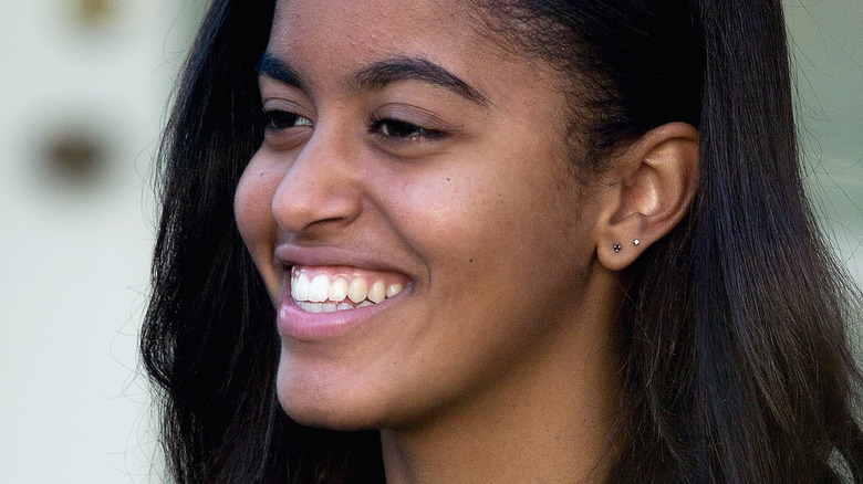 Malia Obama smiles looking away from the camera