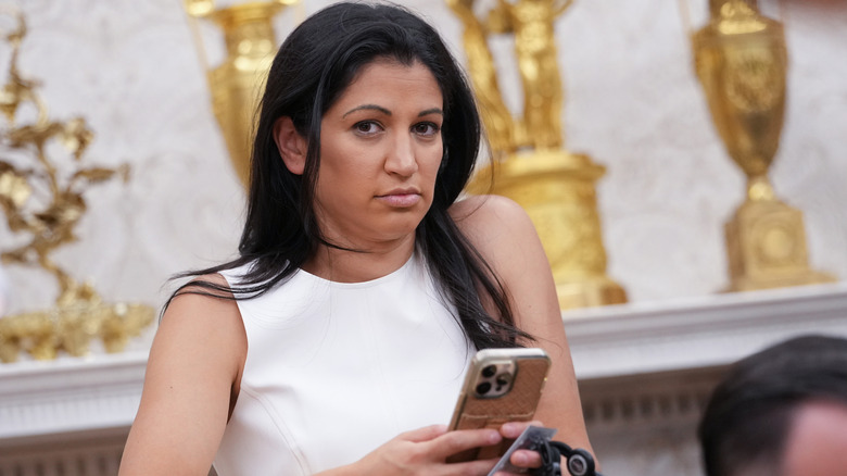 Katie Miller looks up while holding her phone.