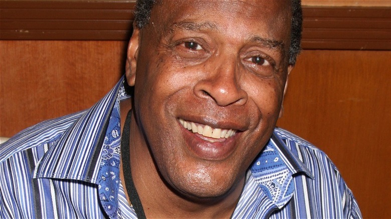 Meshach Taylor, smiling in front of a wooden wall