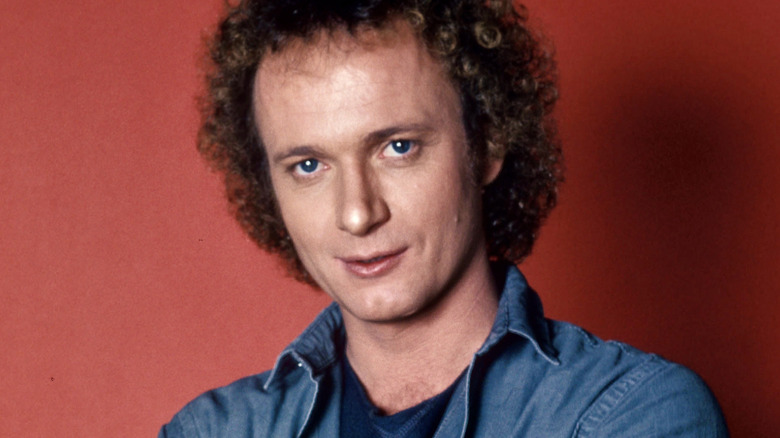 Anthony Geary posing in front of a red background in 1985