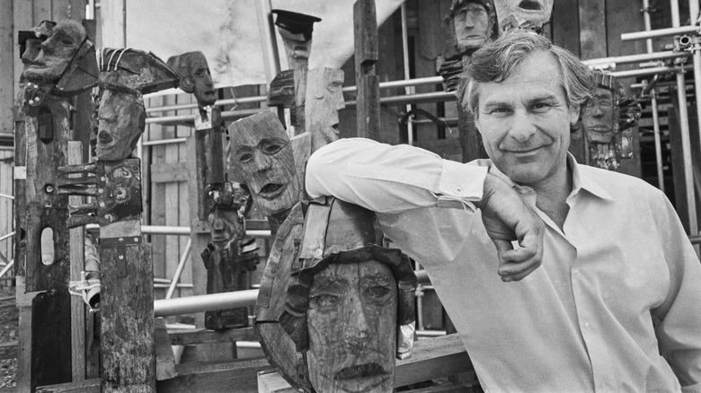 Sam Wanamaker posing with wooden masks.