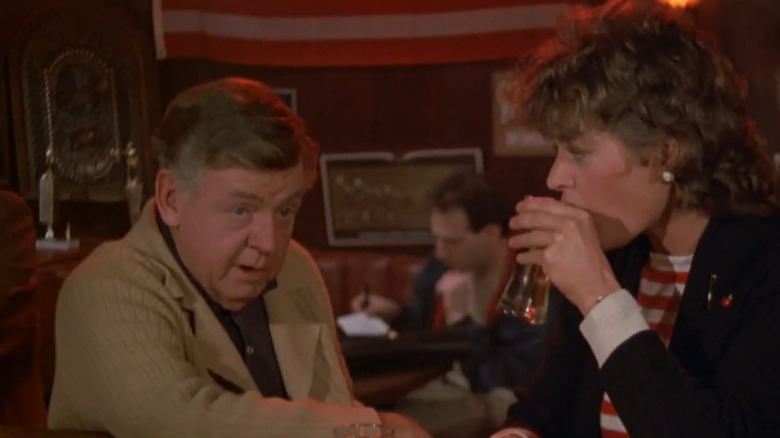 Dick O'Neill in character in a tan jacket and collared polo shirt while at a bar