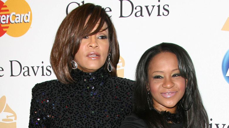 Bobbi Kristina Brown smiling beside Whitney Houston
