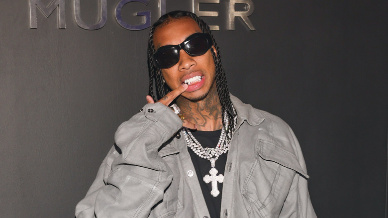 Tyga pointing at teeth grill
