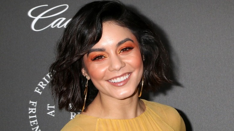 Vanessa Hudgens in a yellow top with gold hoop earrings
