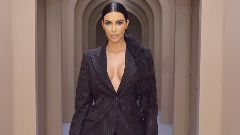 Kim Kardashian with hair in low pony and in a black blazer