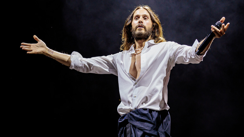 Jared Leto spreading his arms open on a smoky dark stage