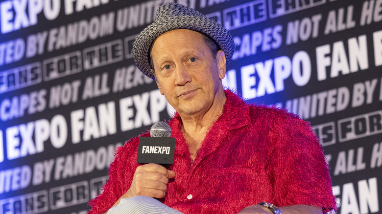 Rob Schneider smiling in a gray fedora