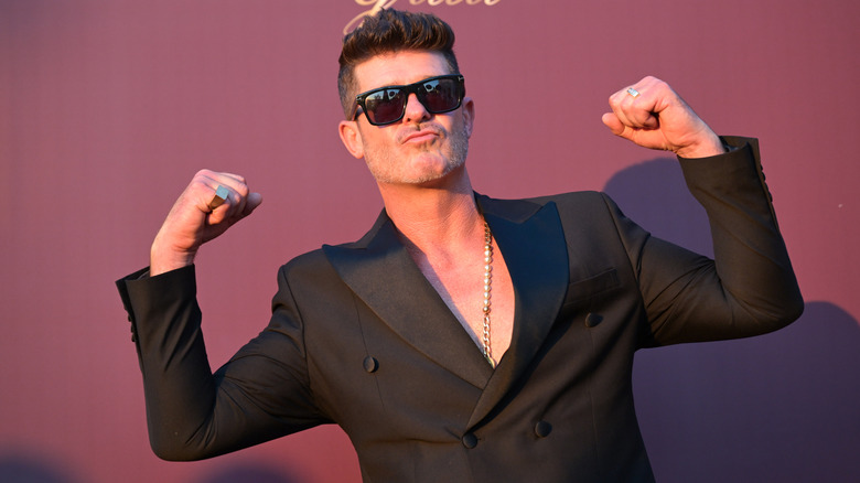 Robin Thicke flexing muscles in a suit jacket