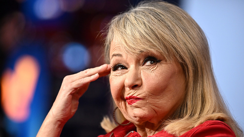 Roseanne Barr wears red and puts her head to her hand on the show Gutfeld