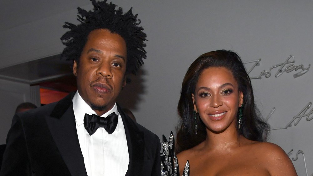 Jay-Z looking serious in a back suit and bow-tie, Beyonce smiling in a black bejeweled dress