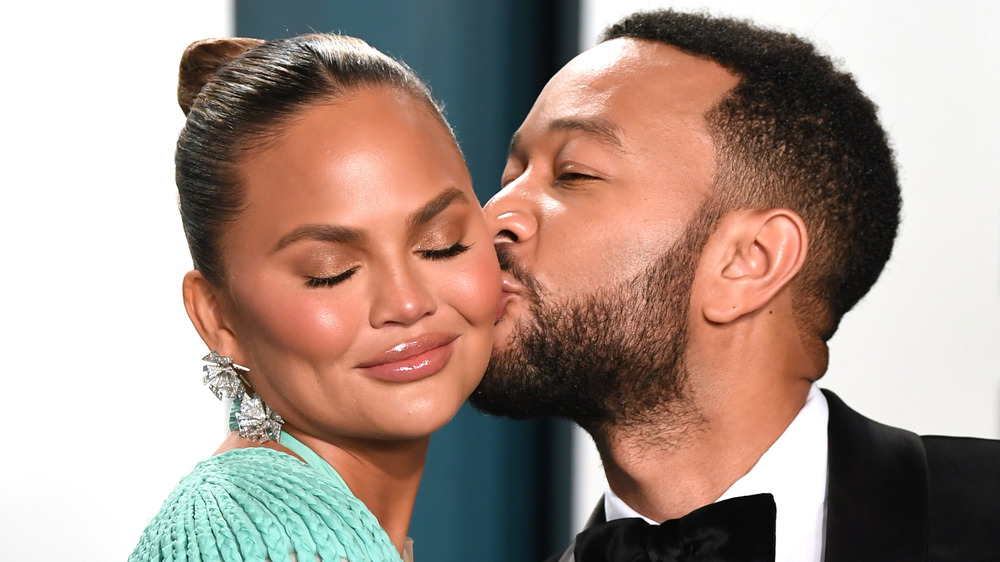 John Legend kissing his wife Chrissy Teigen on the cheek