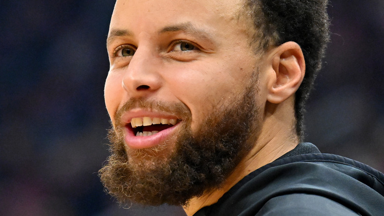 Steph Curry smiles on the court at a 2023 NBA game