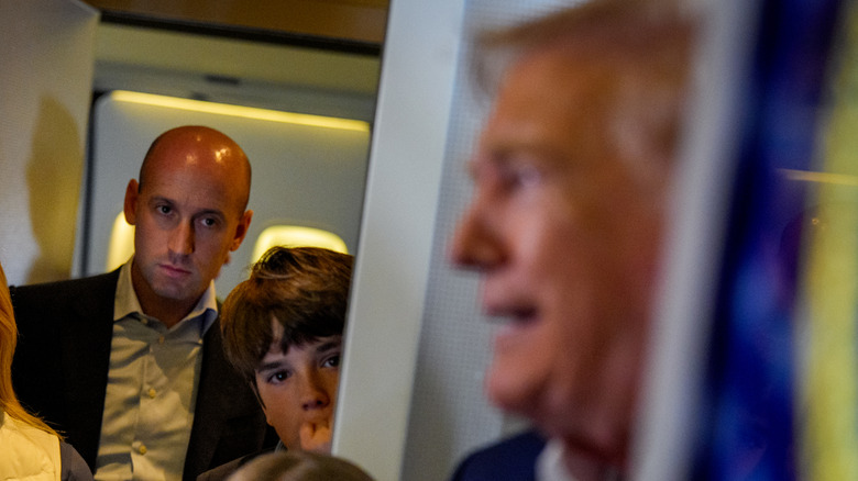 Stephen Miller watches Donald Trump as he speaks to the press.