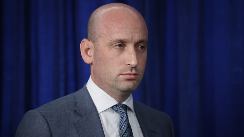 Stephen Miller looks on as Donald Trump speaks to the press