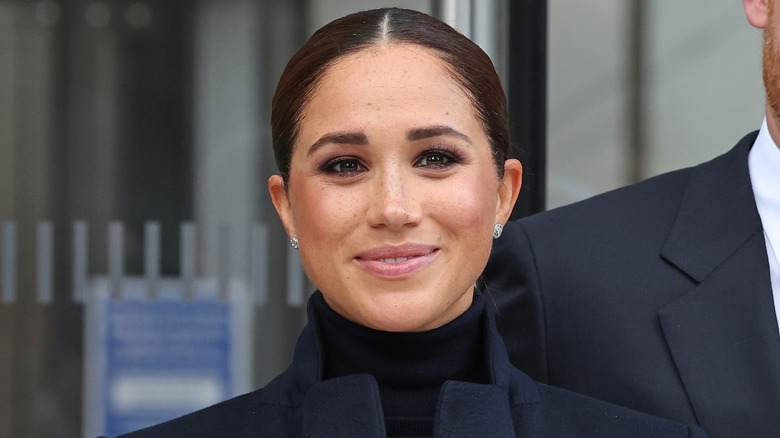 Meghan Markle smiling, wearing an all-black outfit