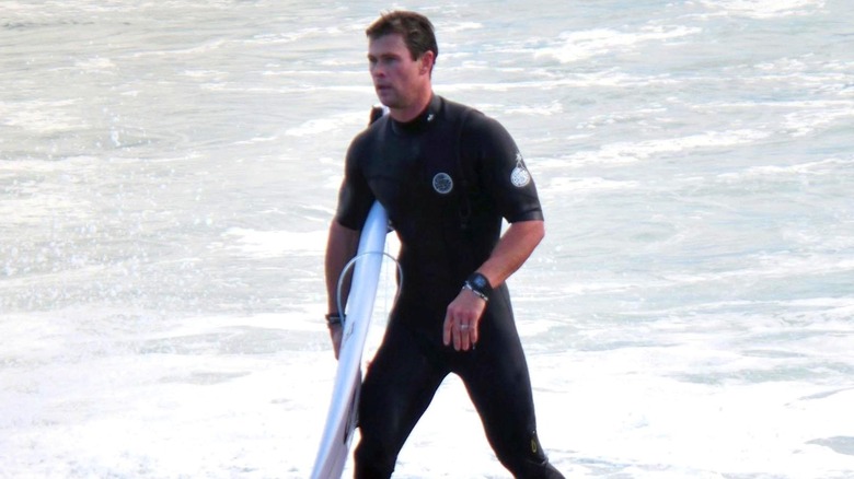 Chris Hemsworth with surfboard, walking